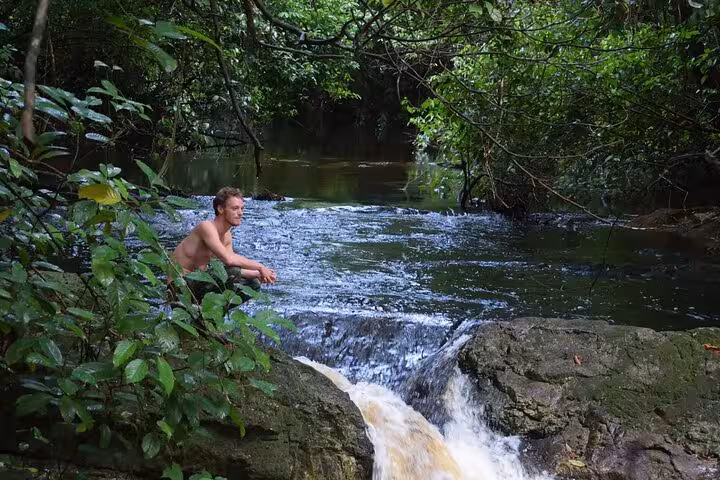 Traveler relaxing by a rainforest stream near Juma Lake Lodge on a 2 days 1 night Amazon getaway