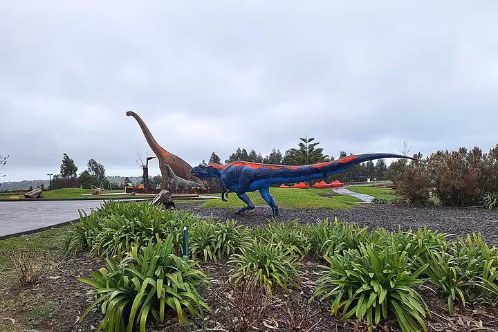 Colorful dinosaur sculptures in scenic landscape at Jurassic Museum of Asturias, ideal for educational tours.