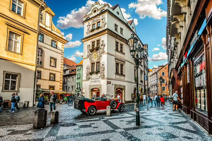 Cobblestone square in Prague Old Town with vintage red car and ornate Baroque buildings