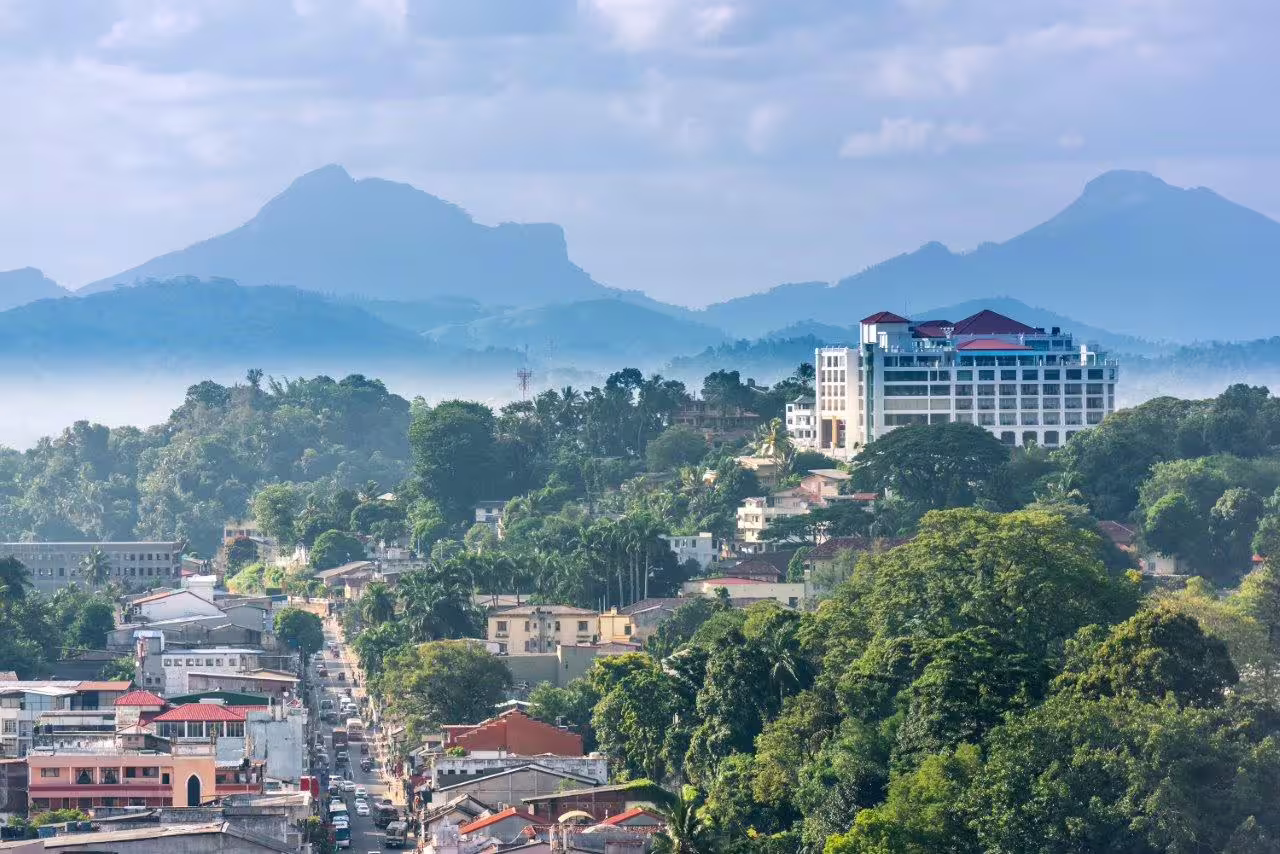 Scenic view of Kandy city with lush greenery and distant mountains, capturing the cultural charm of Sri Lanka.