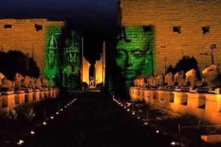 Karnak Temple illuminated at night with green light projections of pharaoh faces during sound and light show