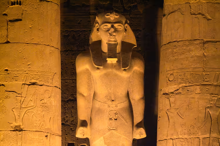 Illuminated ancient Egyptian pharaoh statue at Karnak Temple during the Sound and Light Show at night