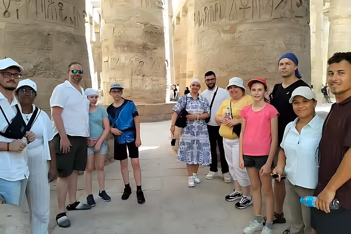 Travelers inside Karnak Temple among giant columns on Cairo to Luxor by plane small group tour with guide