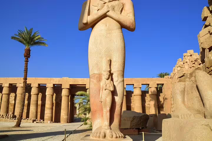 Colossal statue in Karnak Temple complex, Luxor East Bank tour stop with ancient columns under blue sky