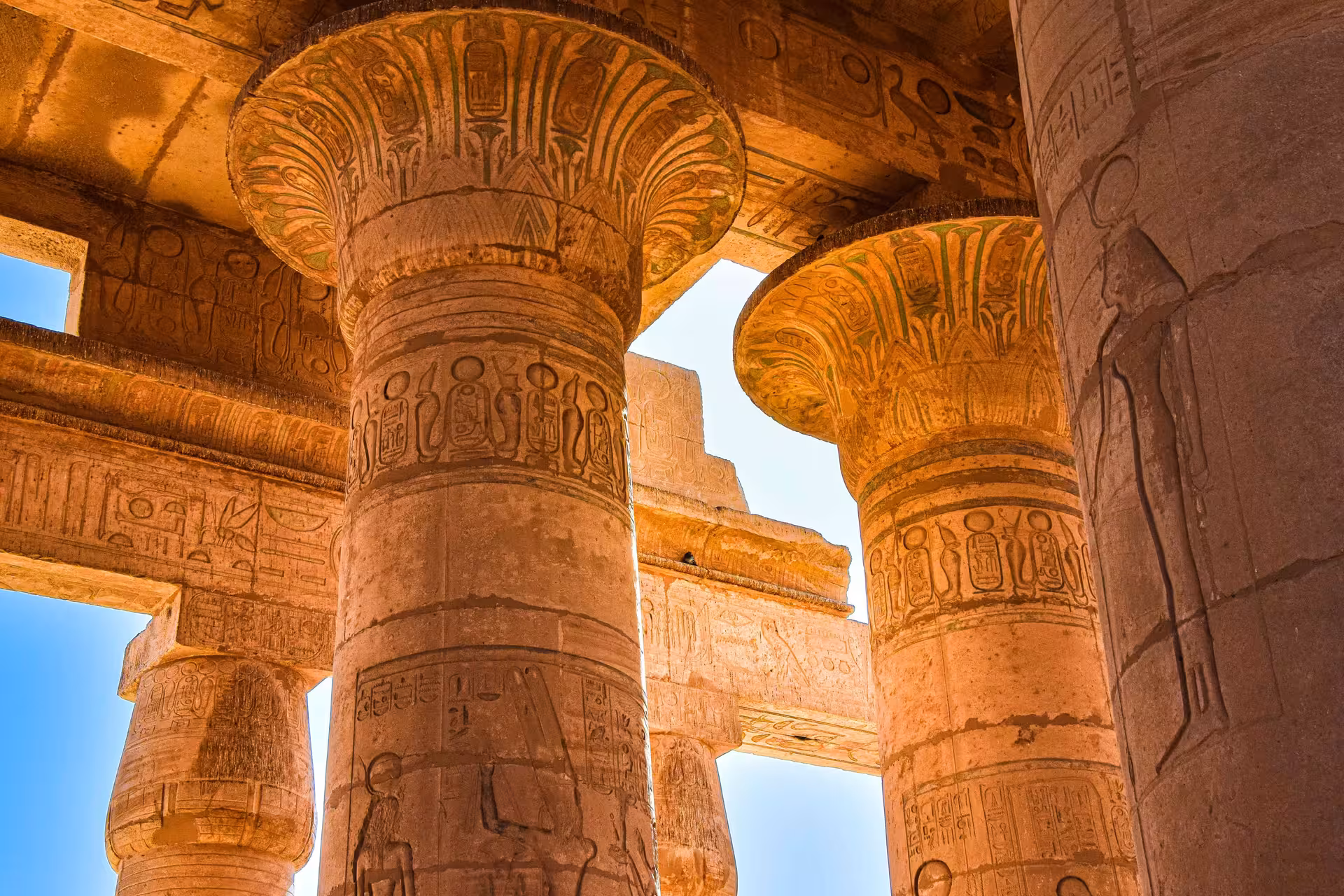 Massive decorated columns with hieroglyphics and painted capitals inside Karnak Temple, Luxor, Egypt