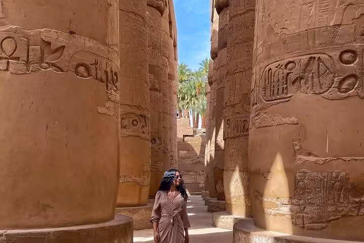 Visitor walking between Karnak Temple columns with hieroglyphs on a private Luxor day trip from Hurghada