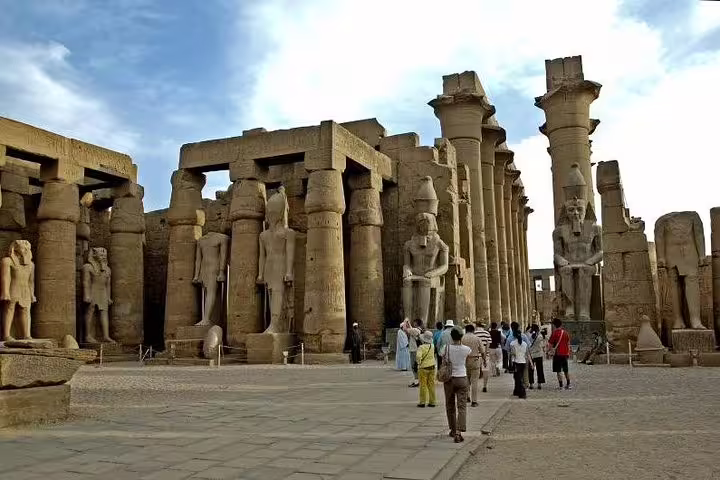 Visitors walk through Karnak Temple columns in Luxor on a full-day East and West Bank highlights tour