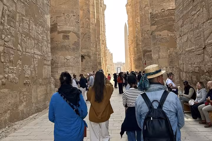 Tourists walk between towering Karnak Temple columns in Luxor on Hurghada day trip with lunch and guide
