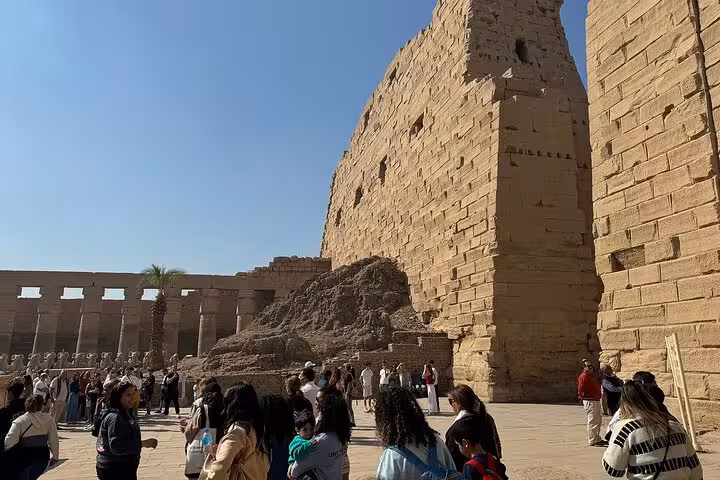Crowds gather at the majestic Karnak Temple, showcasing ancient Egyptian architecture under a clear blue sky.