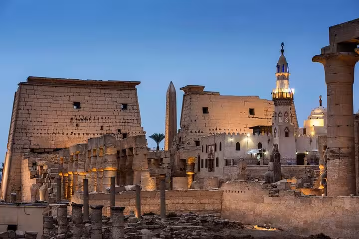 Karnak Temple ruins at dusk with illuminated minaret in Luxor, Cairo to Luxor day tour by flight