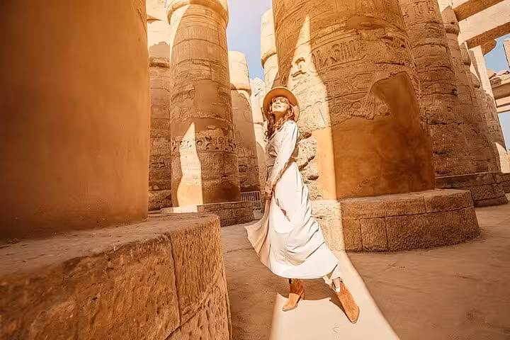 Traveler walking among massive Karnak Temple columns in Luxor, 2-day Hurghada tour with hotel and balloon ride