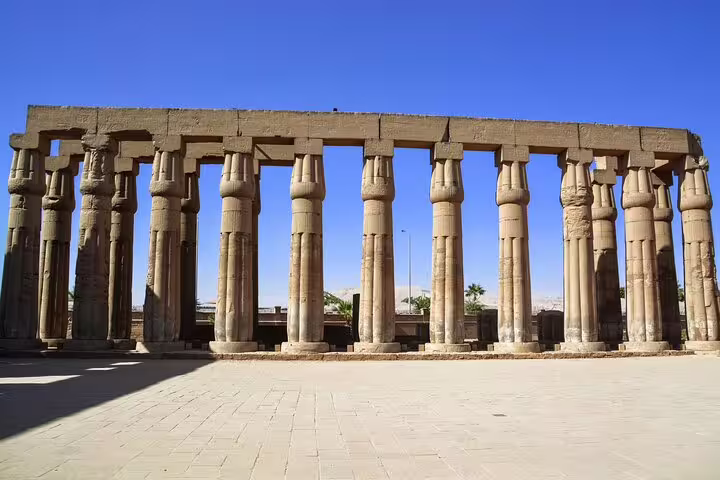 Colonnade of Karnak Temple in Luxor on East Bank Nile tour, towering ancient Egyptian columns under blue sky