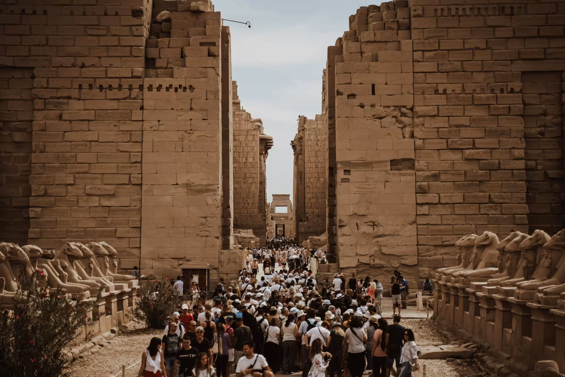 Crowds of tourists walking through the grand entrance of Karnak Temple complex in Luxor, Egypt