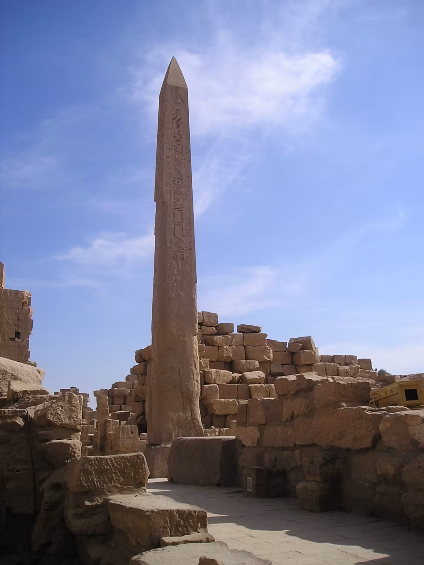 Ancient Egyptian obelisk covered in hieroglyphics standing among stone ruins at Karnak Temple, Luxor