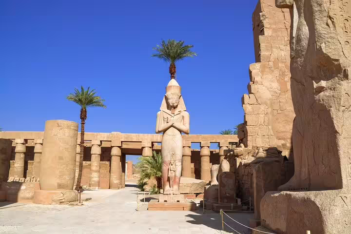 Karnak Temple courtyard with standing pharaoh statue and palm trees, must-see on Splendours of the Nile tour