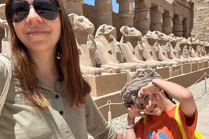 Tourists at Karnak Temple in Luxor beside ram-headed sphinx statues on a private Egypt sightseeing tour