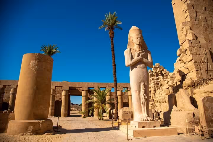 Ramses II statue and palm-lined ruins at Karnak Temple complex, Luxor day trip from Hurghada with tickets