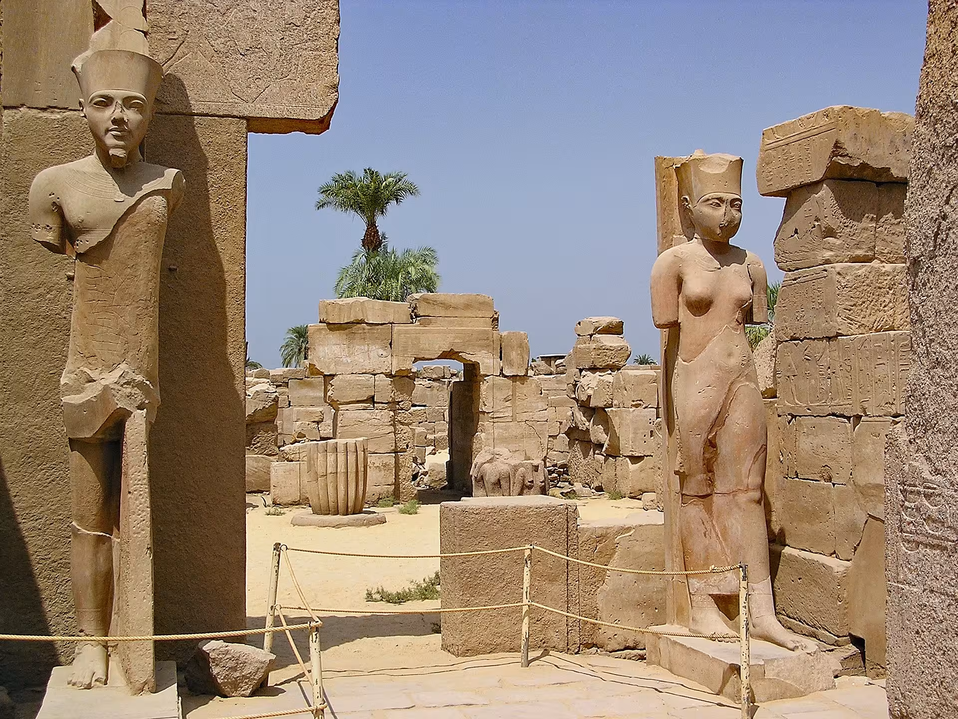 Ancient Egyptian statues and ruins at Karnak Temple complex in Luxor, Egypt under clear blue sky