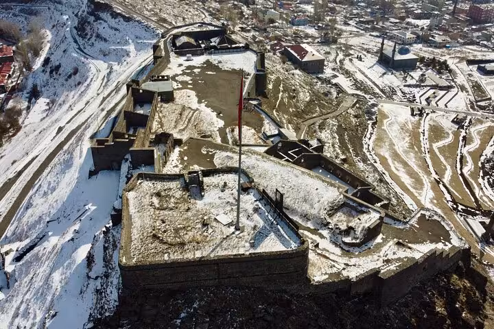 Aerial view of snow-covered Kars Castle with Turkish flag, key stop on an all-inclusive private guided tour