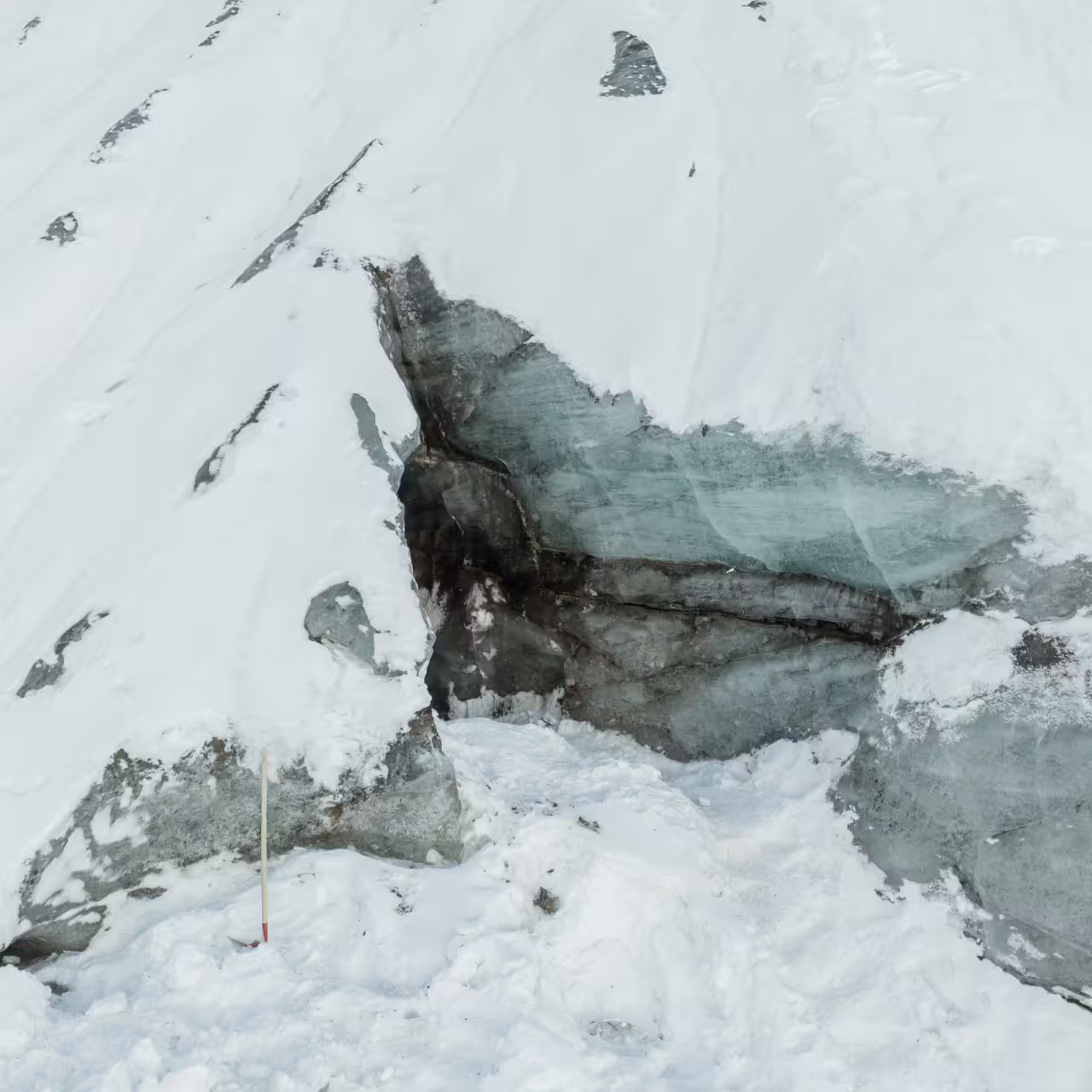 Close-up of Katla glacier ice cave entrance revealing layered blue ice beneath snow on Iceland South Coast tour