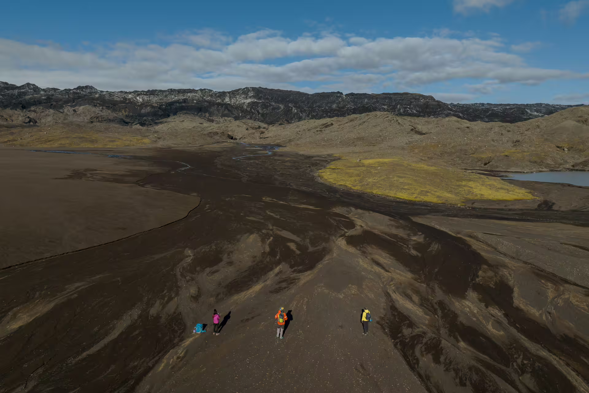 A guide leads a small group across Katla volcanic black sand terrain during an immersive glacier research tour in Iceland.
