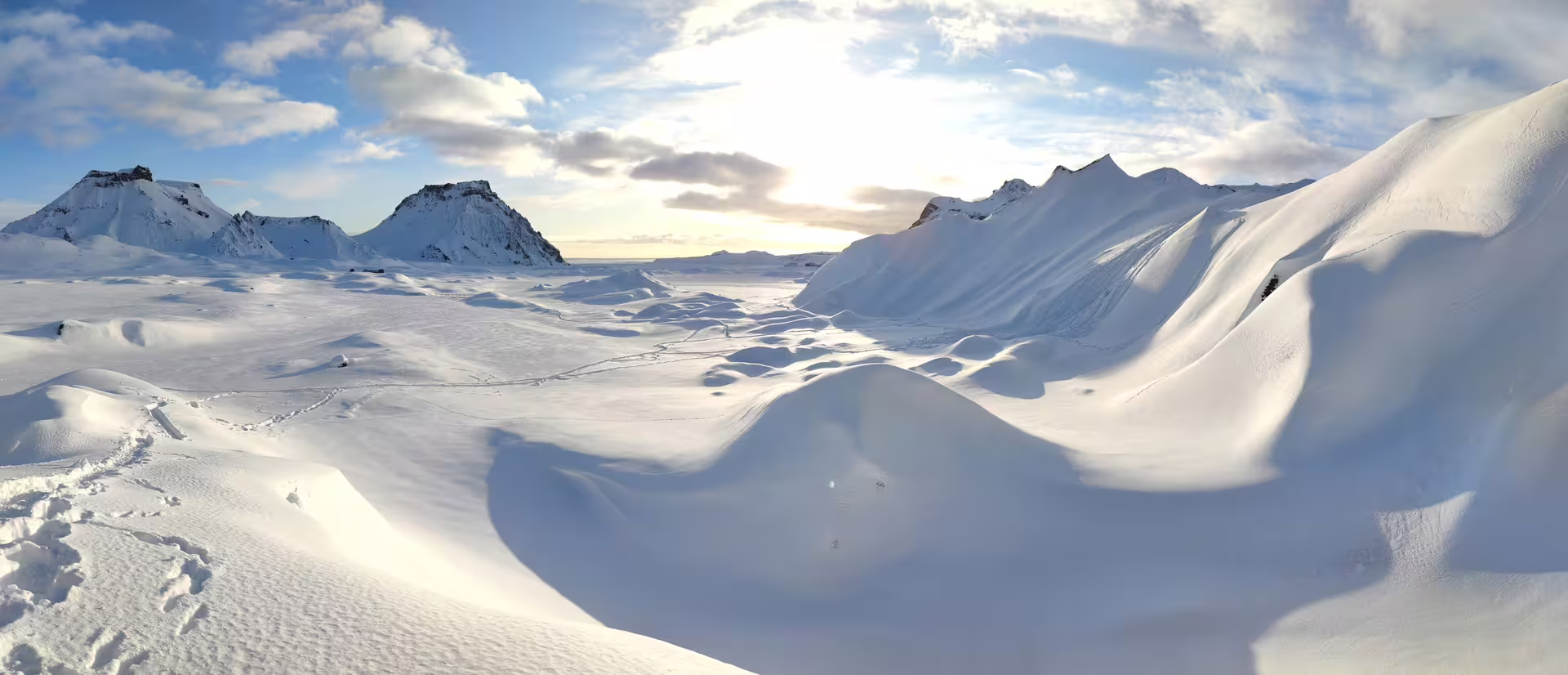 Vast snow-covered glacier landscape with dramatic mountain peaks under a bright winter sky near Katla, Iceland