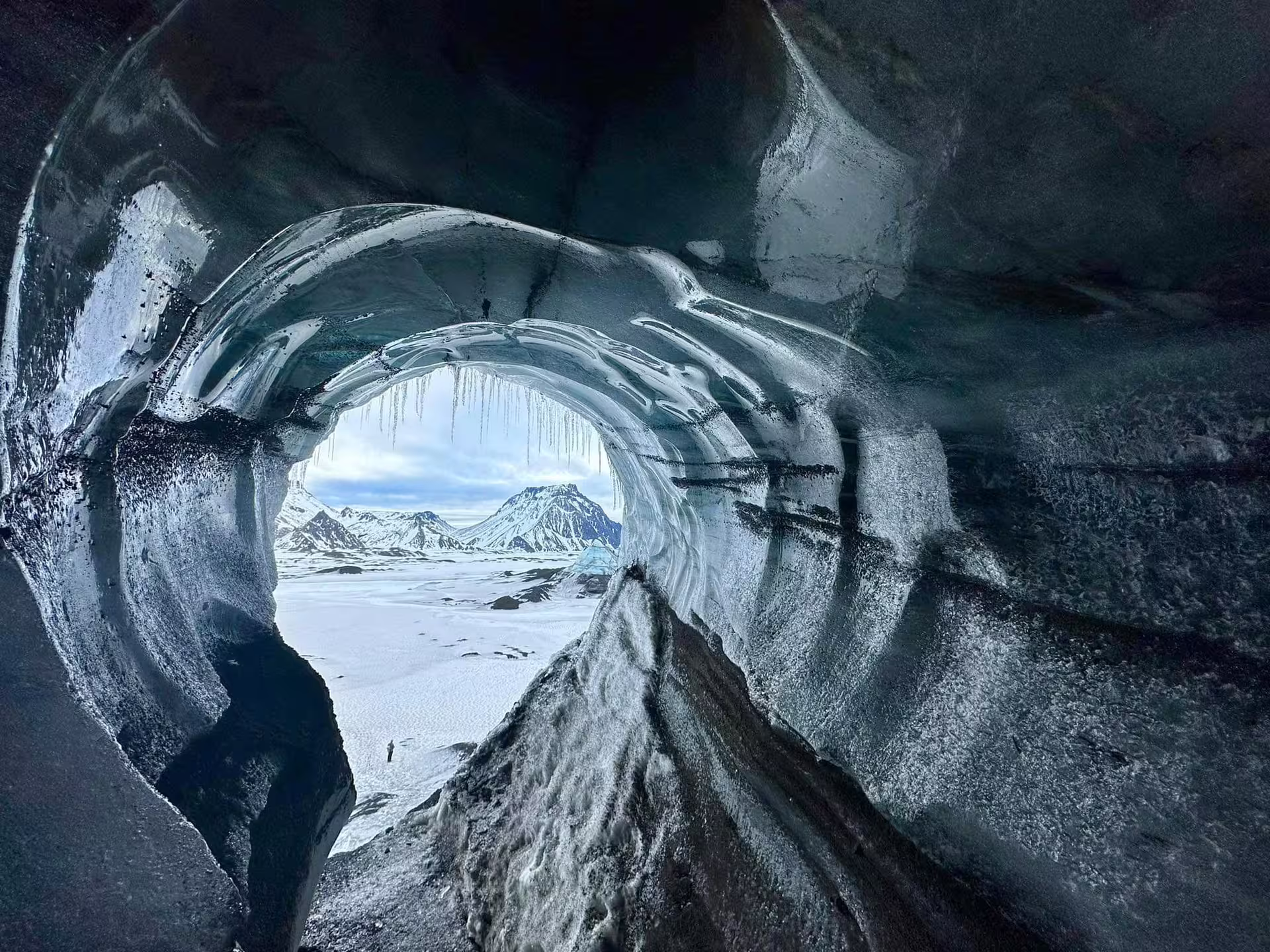 Dramatic Katla ice cave arch frames snowy Iceland mountains and frozen landscape on a South Coast glacier tour