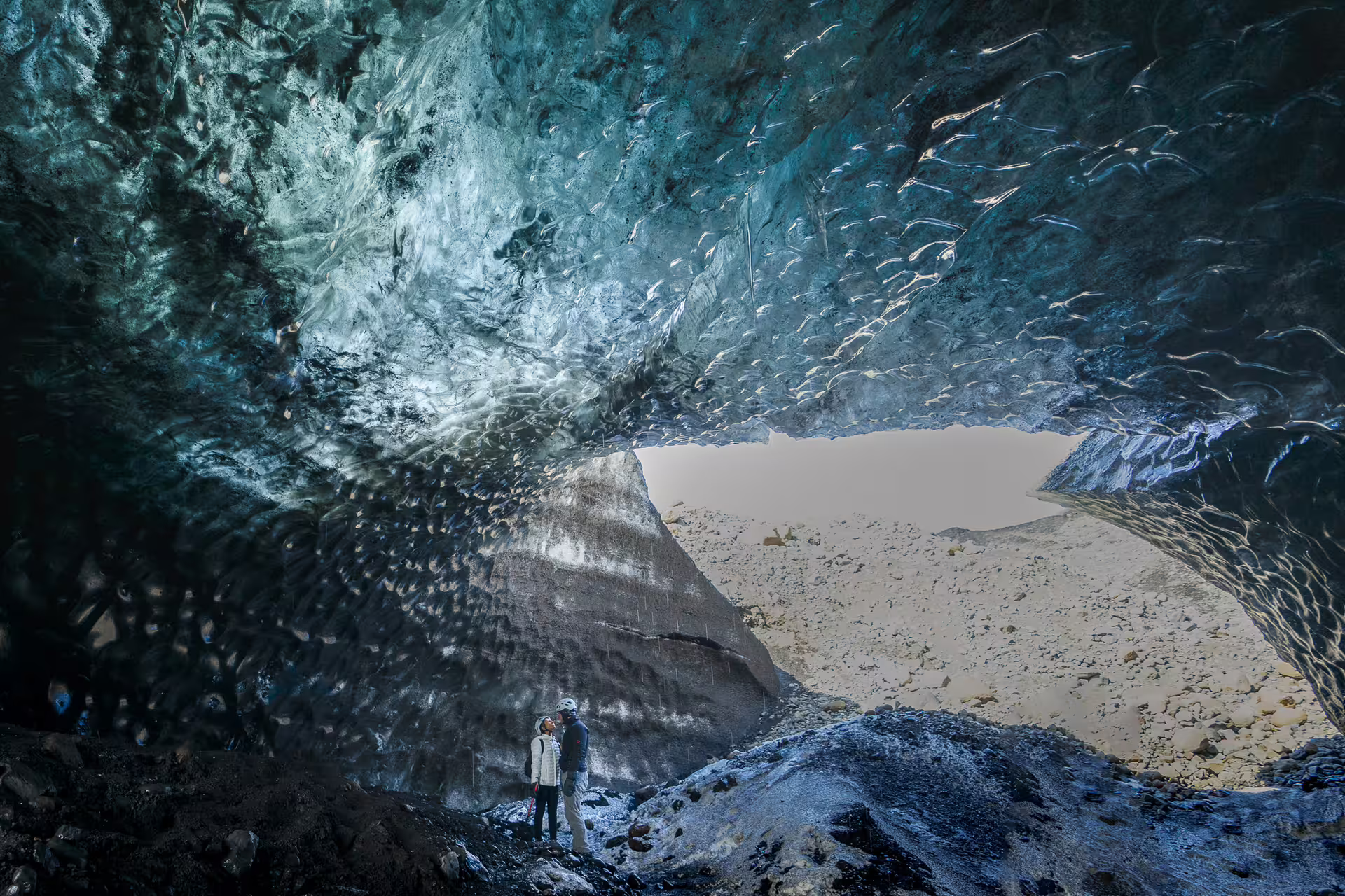 Two explorers gazing up at stunning blue glacial ice formations inside Katla Ice Cave near Vik Iceland