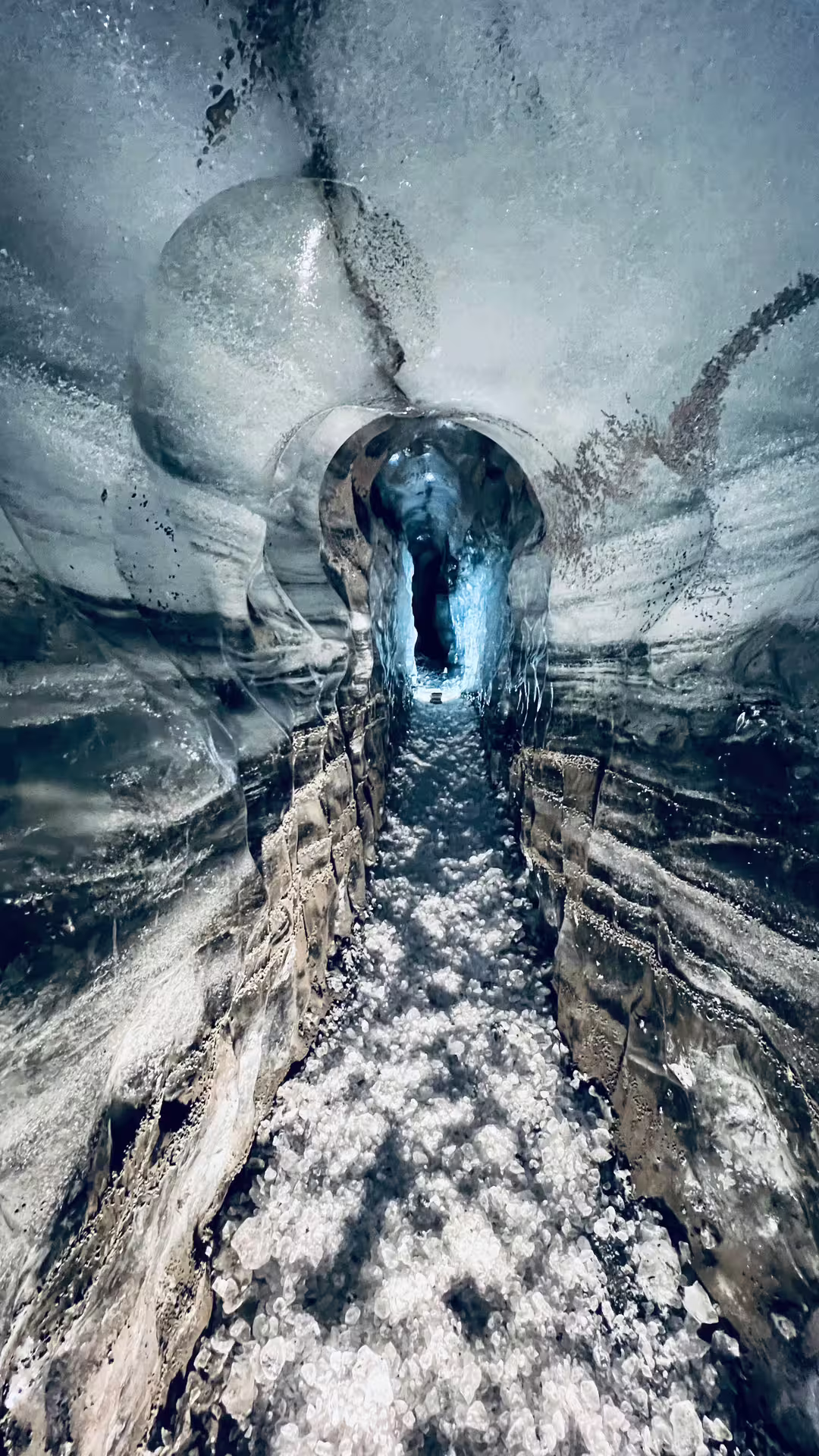 Narrow glowing blue ice tunnel passage inside Katla ice cave on Iceland South Coast day tour from Reykjavik