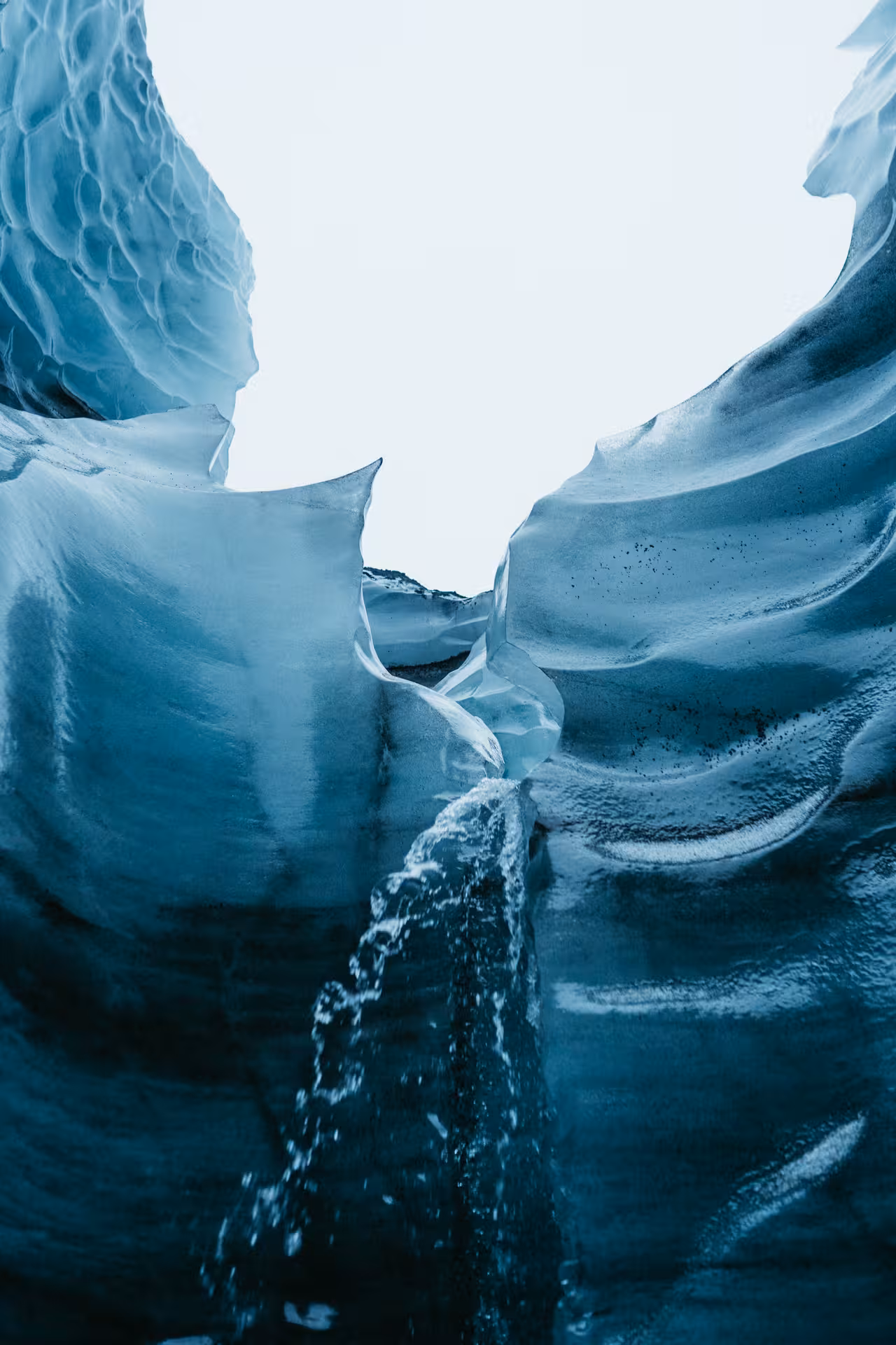 Blue Katla ice cave corridor with meltwater stream on a private guided tour near Vík, Iceland