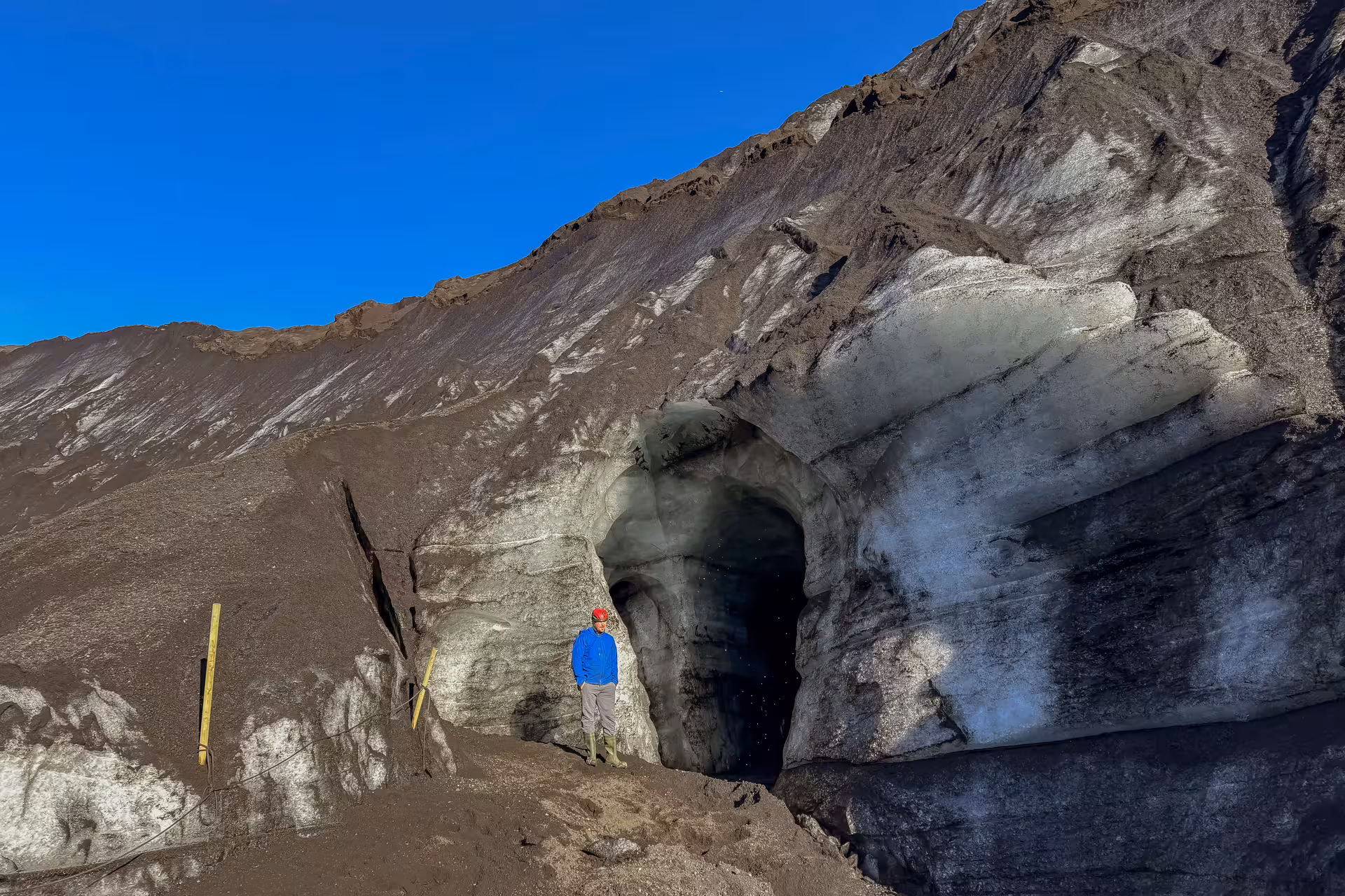 Guide standing at the dramatic entrance of Katla ice cave on Myrdalsjokull Glacier during a day trip from Vik Iceland