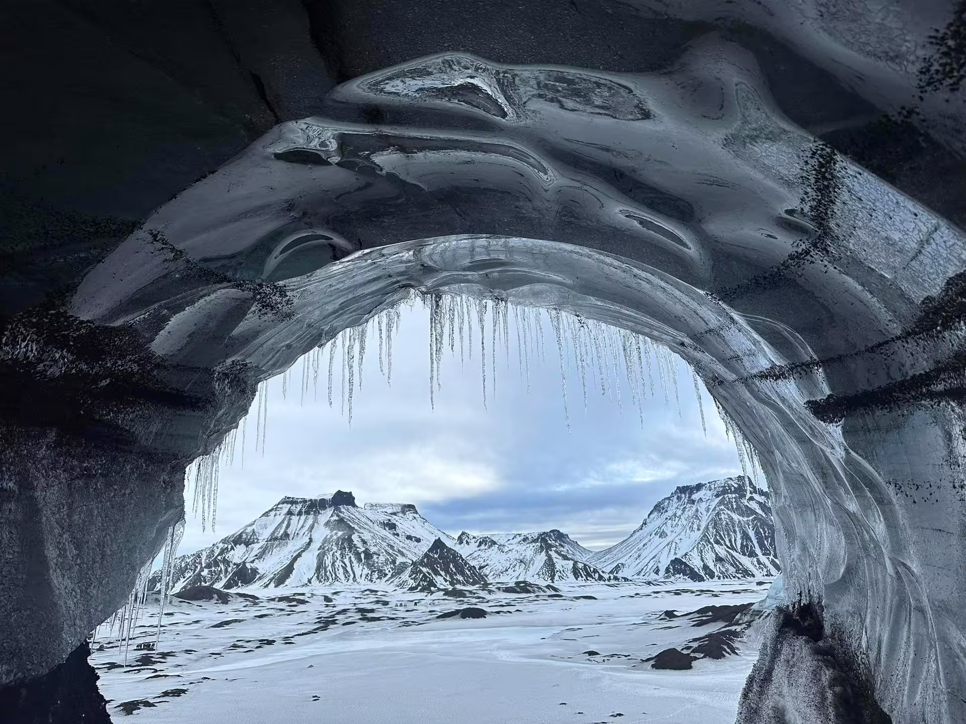 Stunning Katla ice cave interior with icicles framing snow-covered Iceland mountains on a guided glacier tour