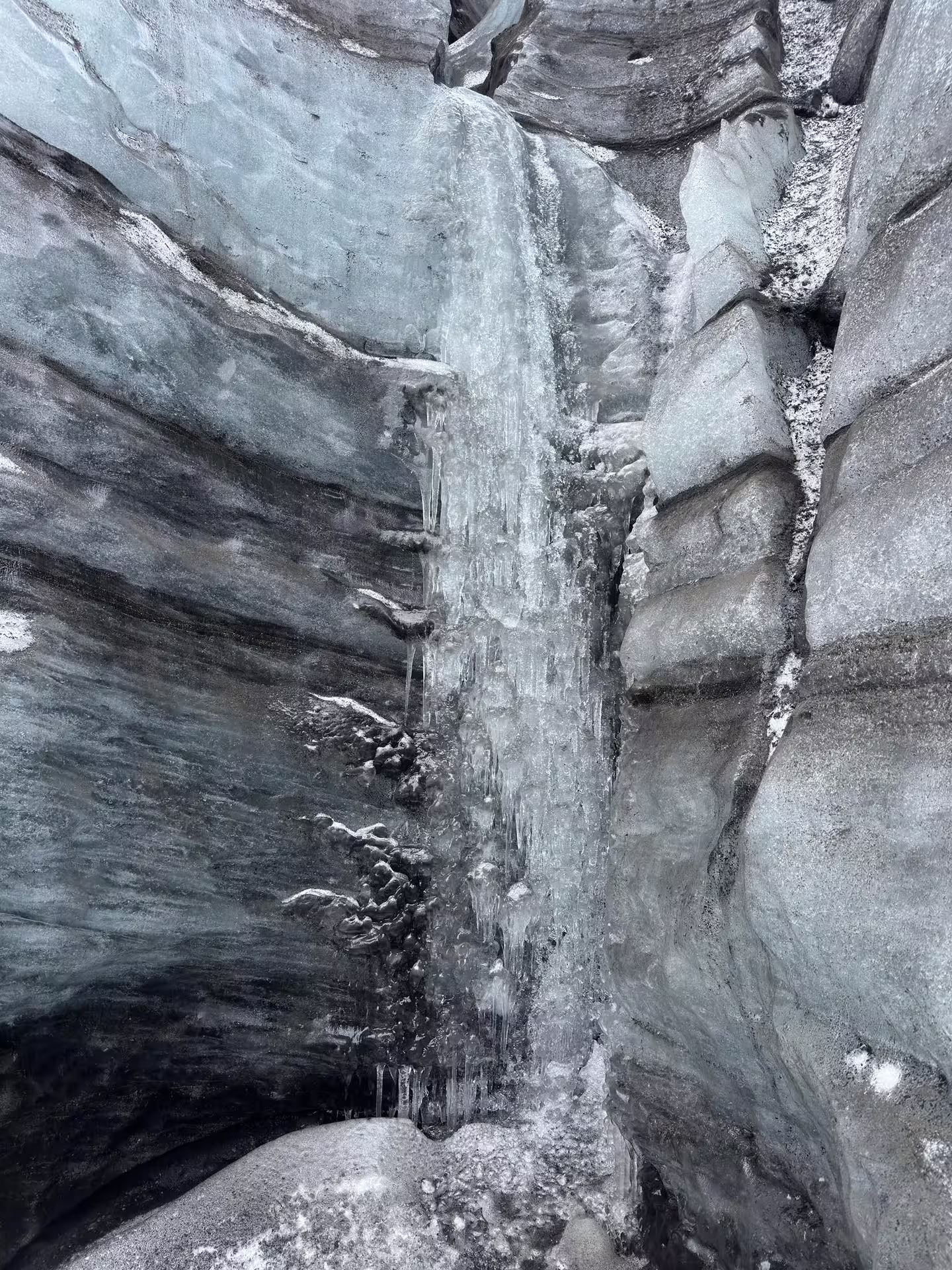 Frozen icicles cascading down layered glacier walls inside Katla ice cave on Myrdalsjokull guided tour from Vik