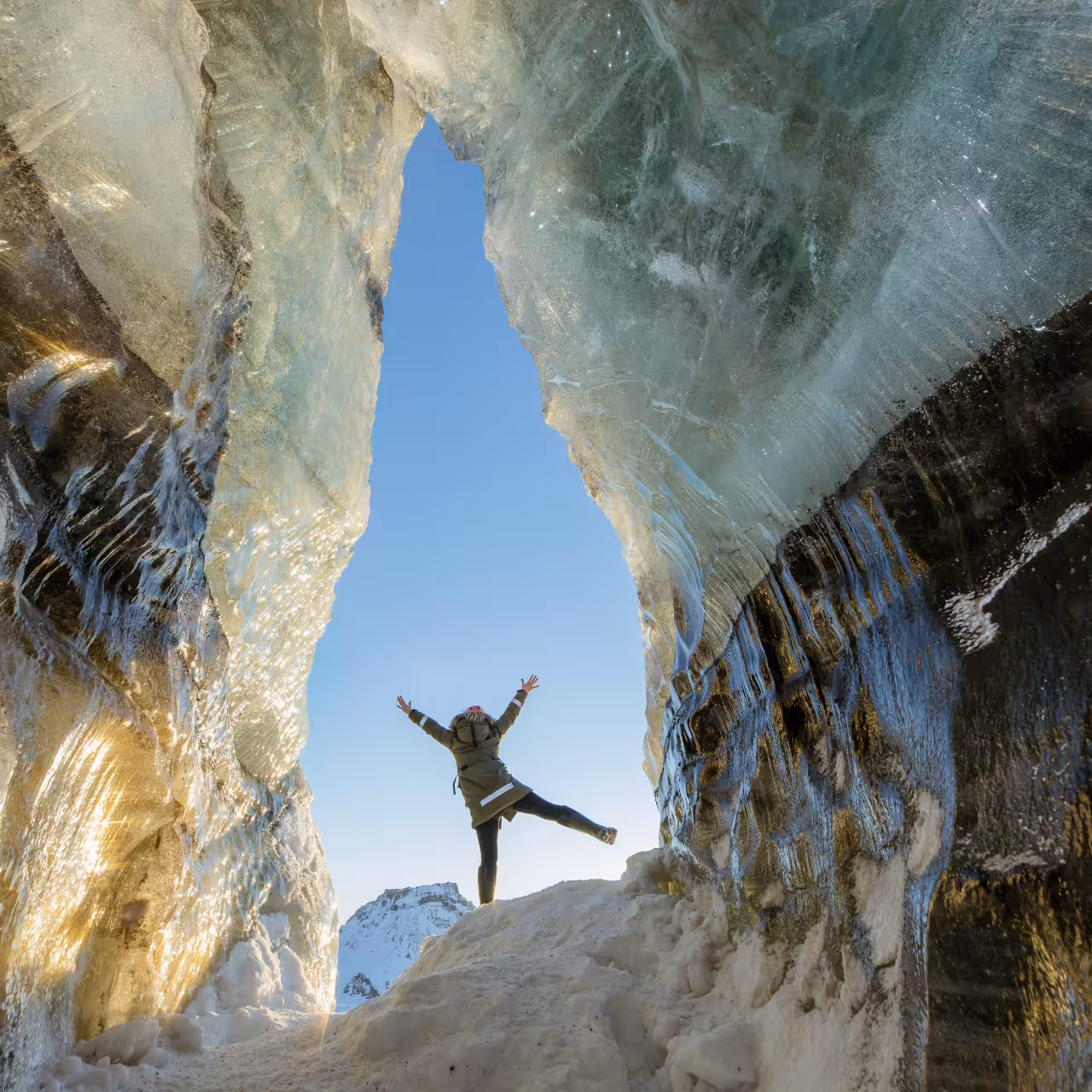Excited traveler posing inside the stunning Katla ice cave on Myrdalsjokull Glacier day trip from Vik Iceland