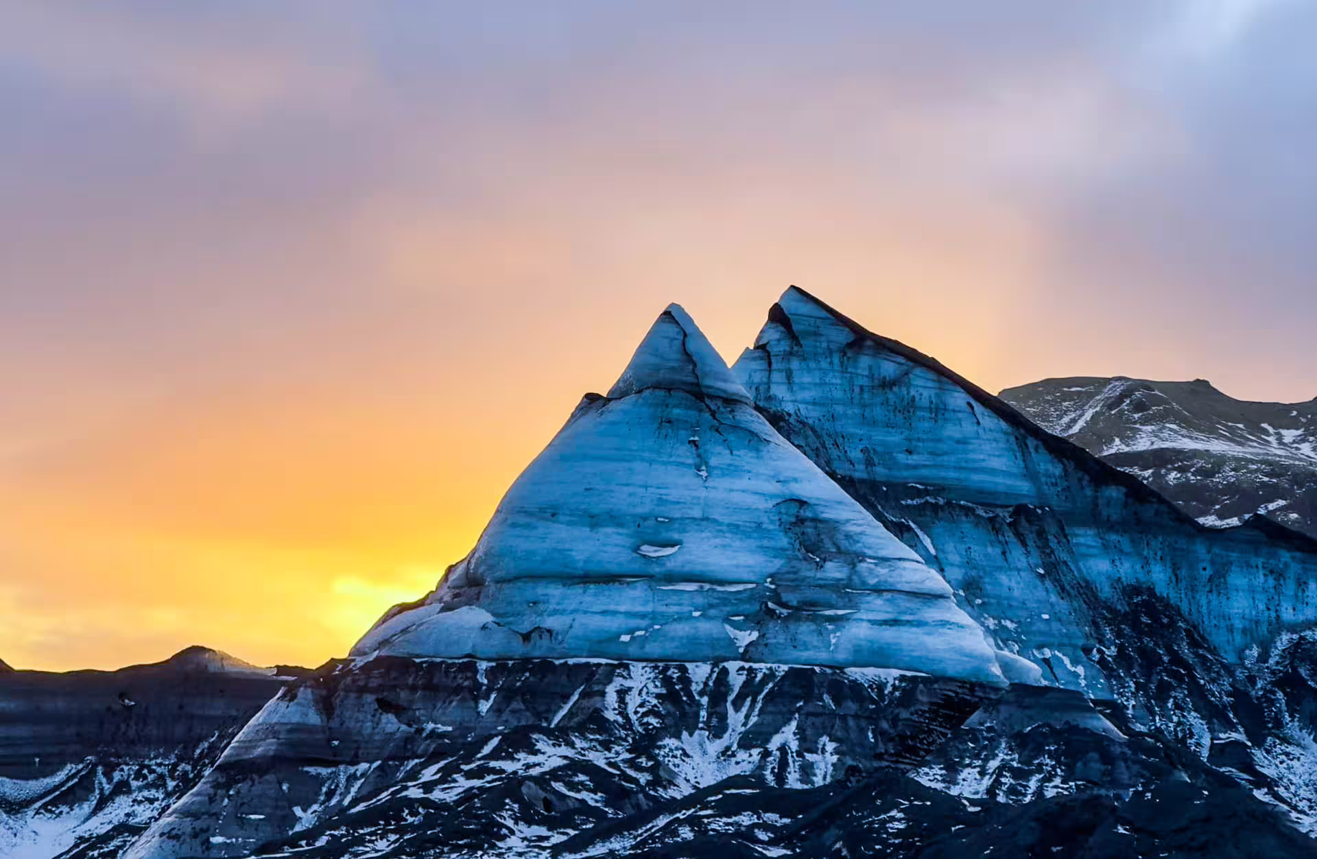 Stunning Katla glacier ice formations silhouetted against a vivid orange sunset sky on Iceland South Coast tour