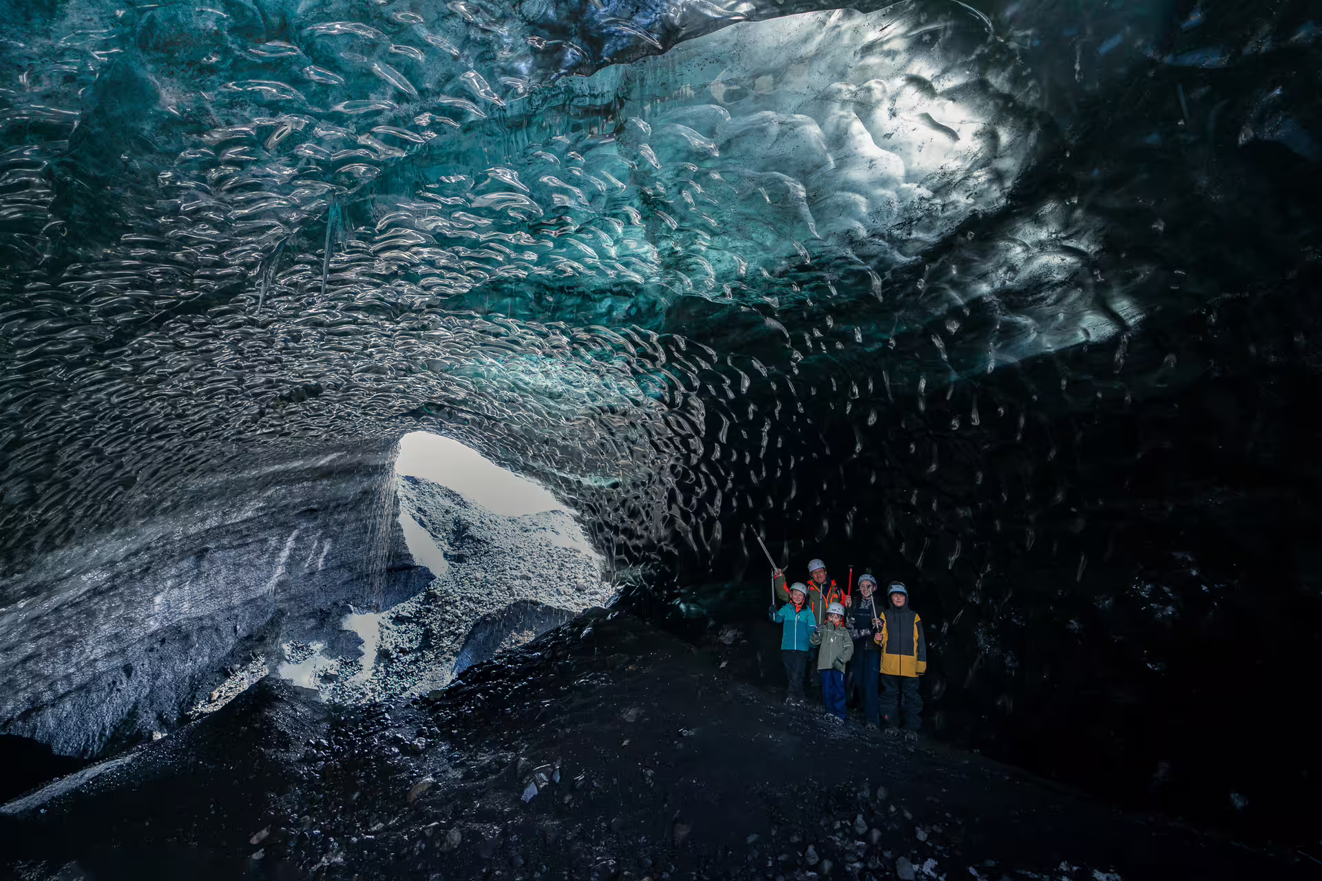 Group of tourists with helmets exploring the stunning blue ice cave at Katla glacier in Iceland