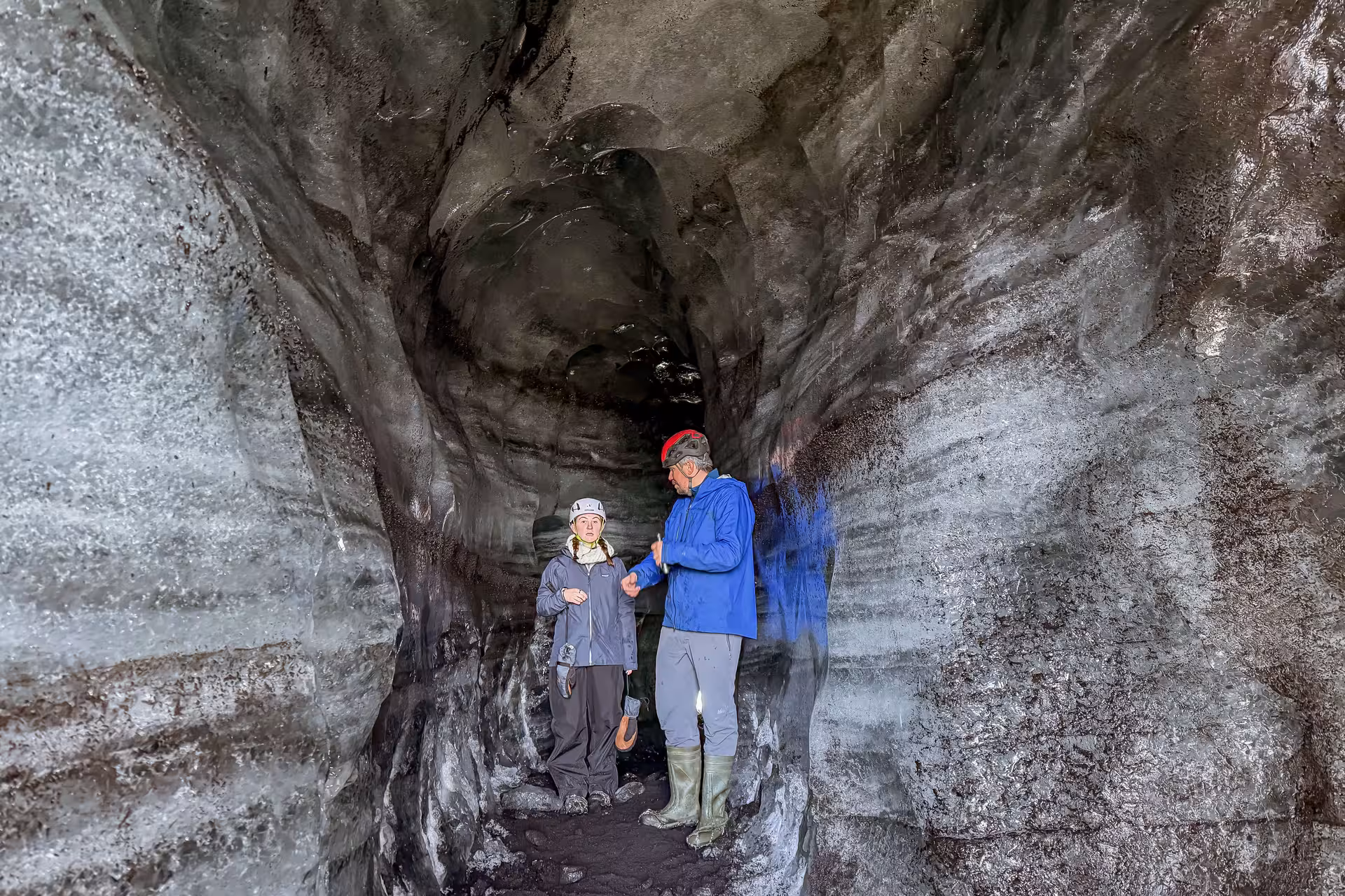 A guide and tourist explore the dark volcanic ice tunnel inside Katla ice cave on Myrdalsjokull Glacier near Vik Iceland.