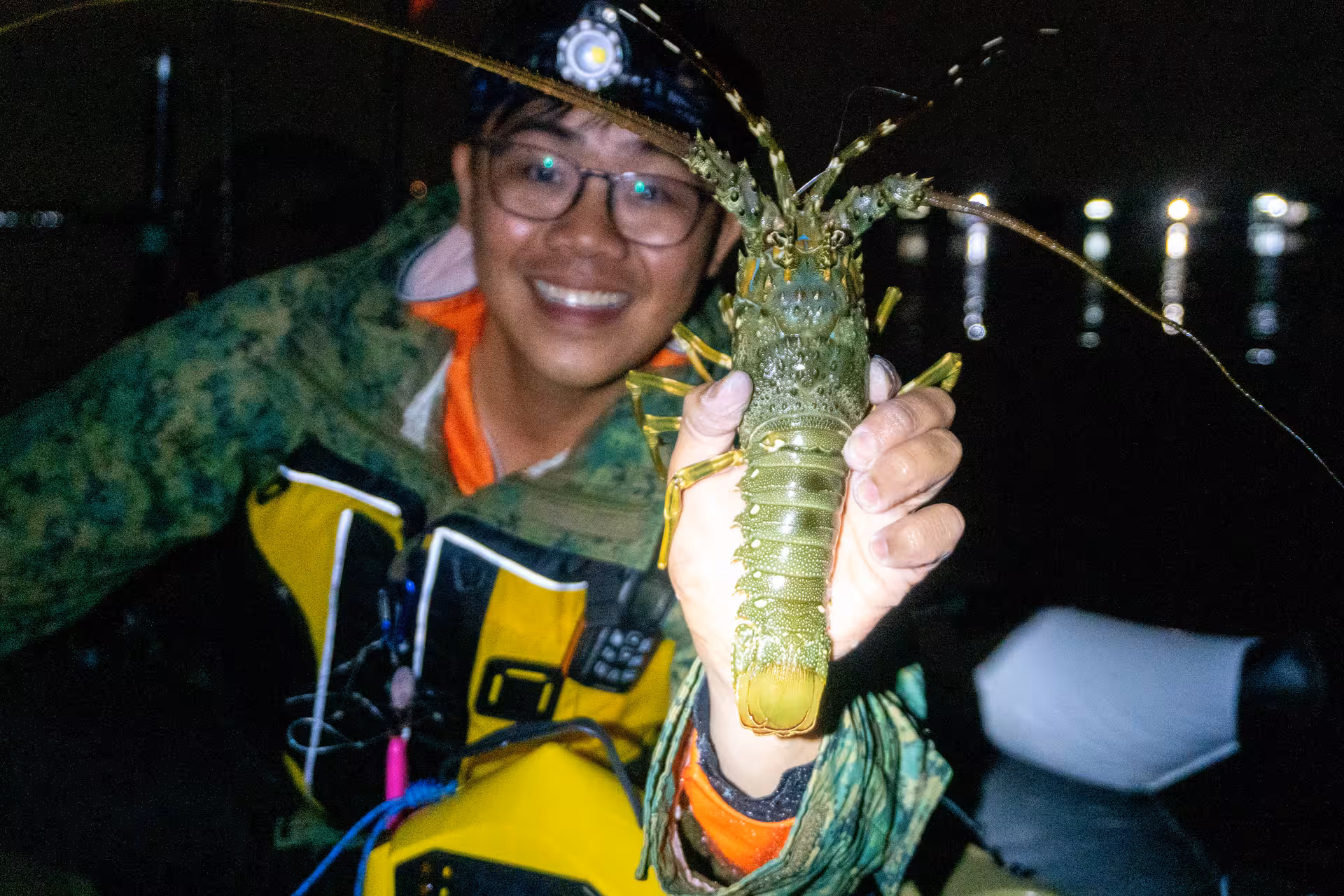 Kayaker showcases vibrant green lobster caught at night, highlighting the unique marine life of Pulau Ubin.