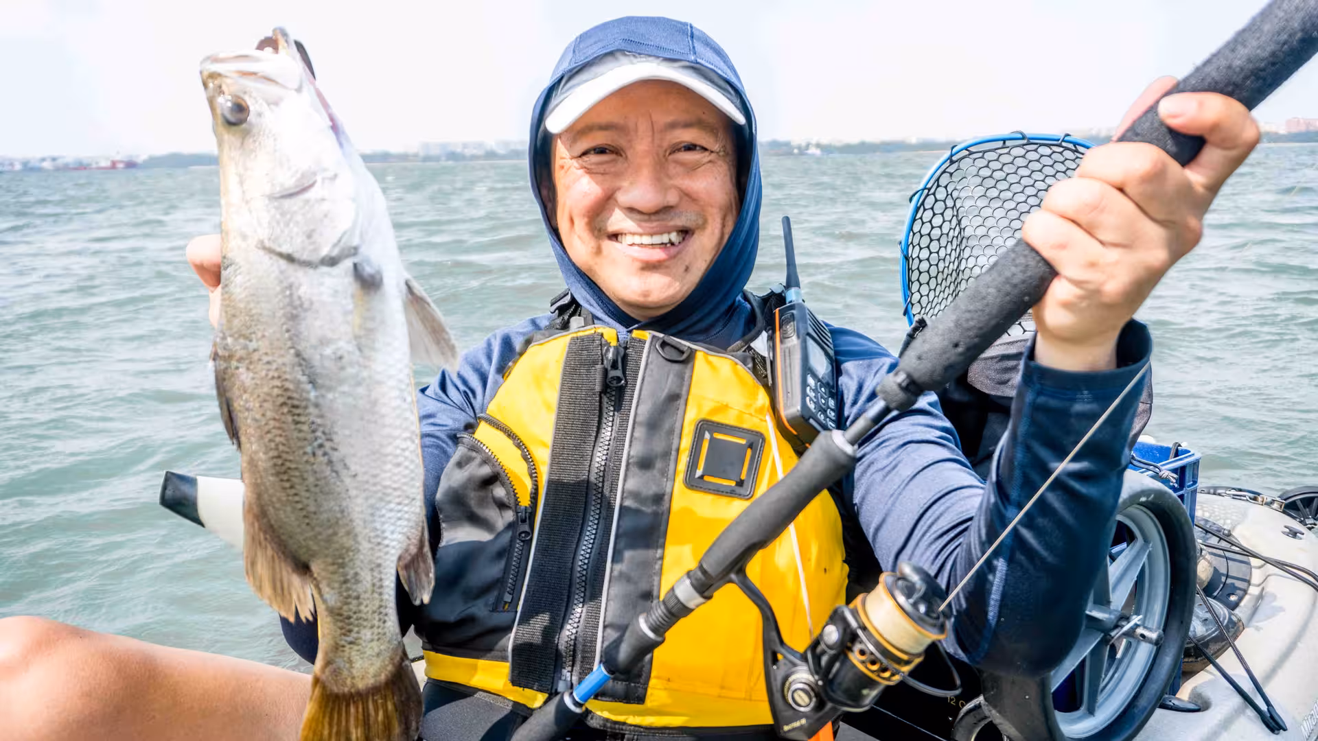 Happy kayaker displays a freshly caught fish amidst the scenic waters of Pulau Ubin mangroves.