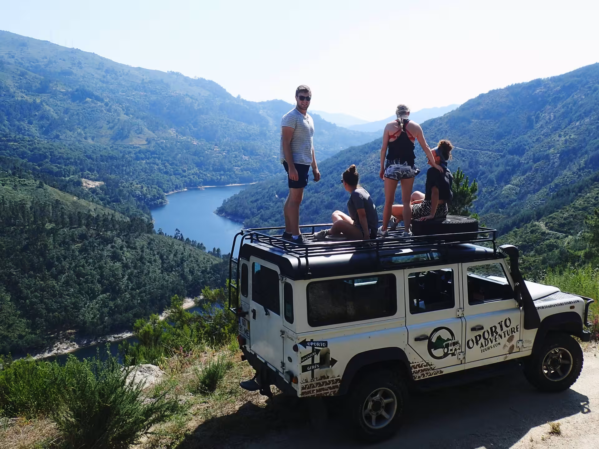 Adventurers on a jeep enjoy breathtaking views of Peneda Geres National Park's lush valley and river.