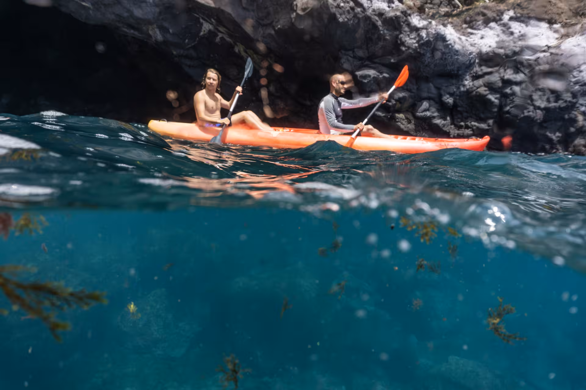 Kayaking adventure near rocky cliffs with snorkeling opportunities in clear, vibrant waters.