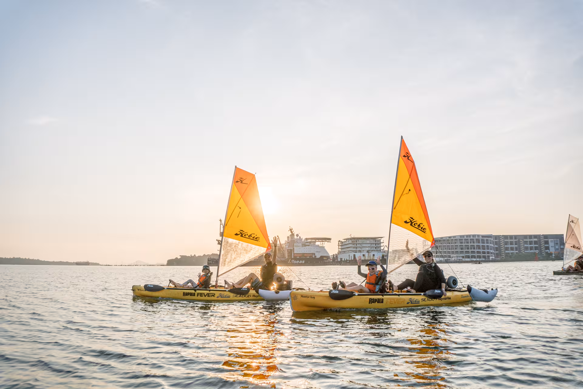 Kayak sailing at sunset with colorful sails and calm waters creating a picturesque adventure.