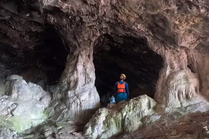 Adventurer in a vibrant life vest explores a stunning coastal cave during a kayak and snorkeling tour in Lisbon, Portugal.