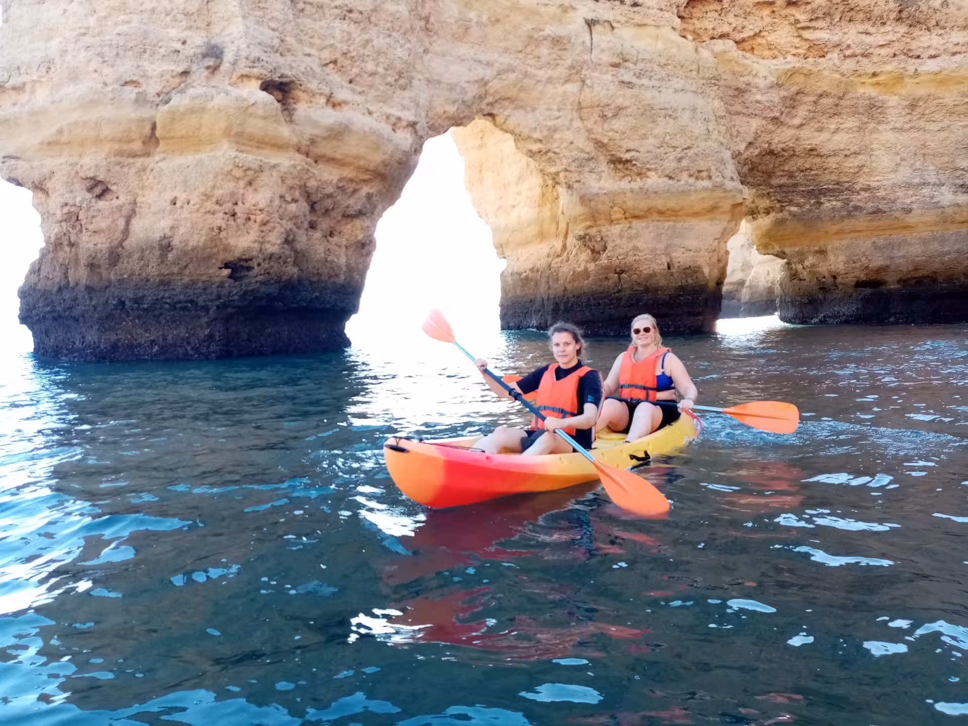 Two kayakers exploring the majestic rock arches of Benagil, Algarve, experiencing a scenic kayak tour.