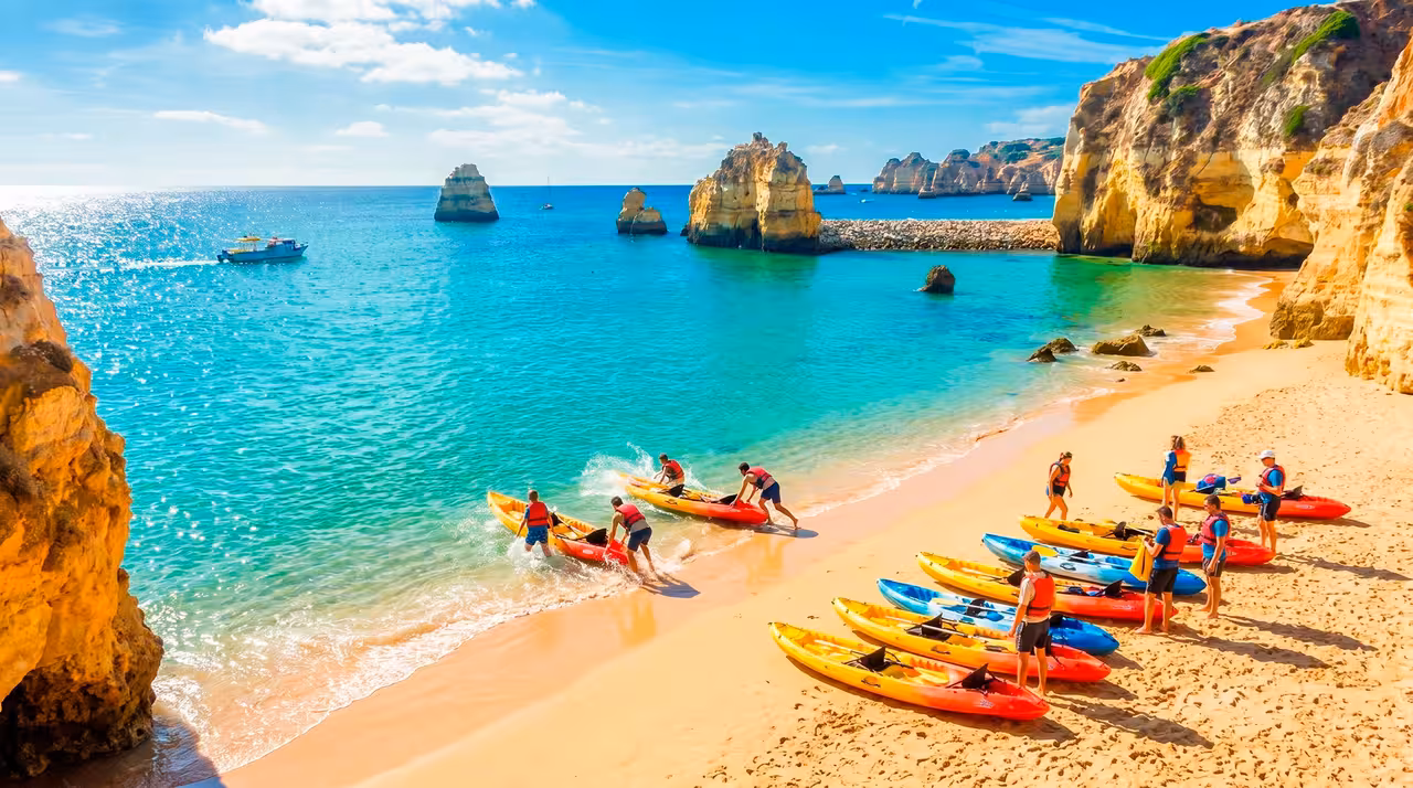 Colorful kayaks and tour group launching into turquoise waters at Ponta da Piedade golden cliffs Lagos Algarve