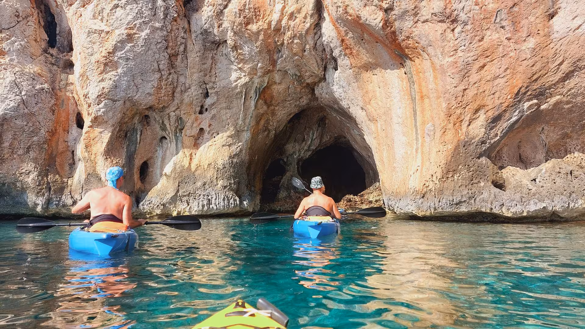 Kayakers venture into a sea cave in Porto Conte Park, Alghero, enjoying an adventurous tour on clear waters.