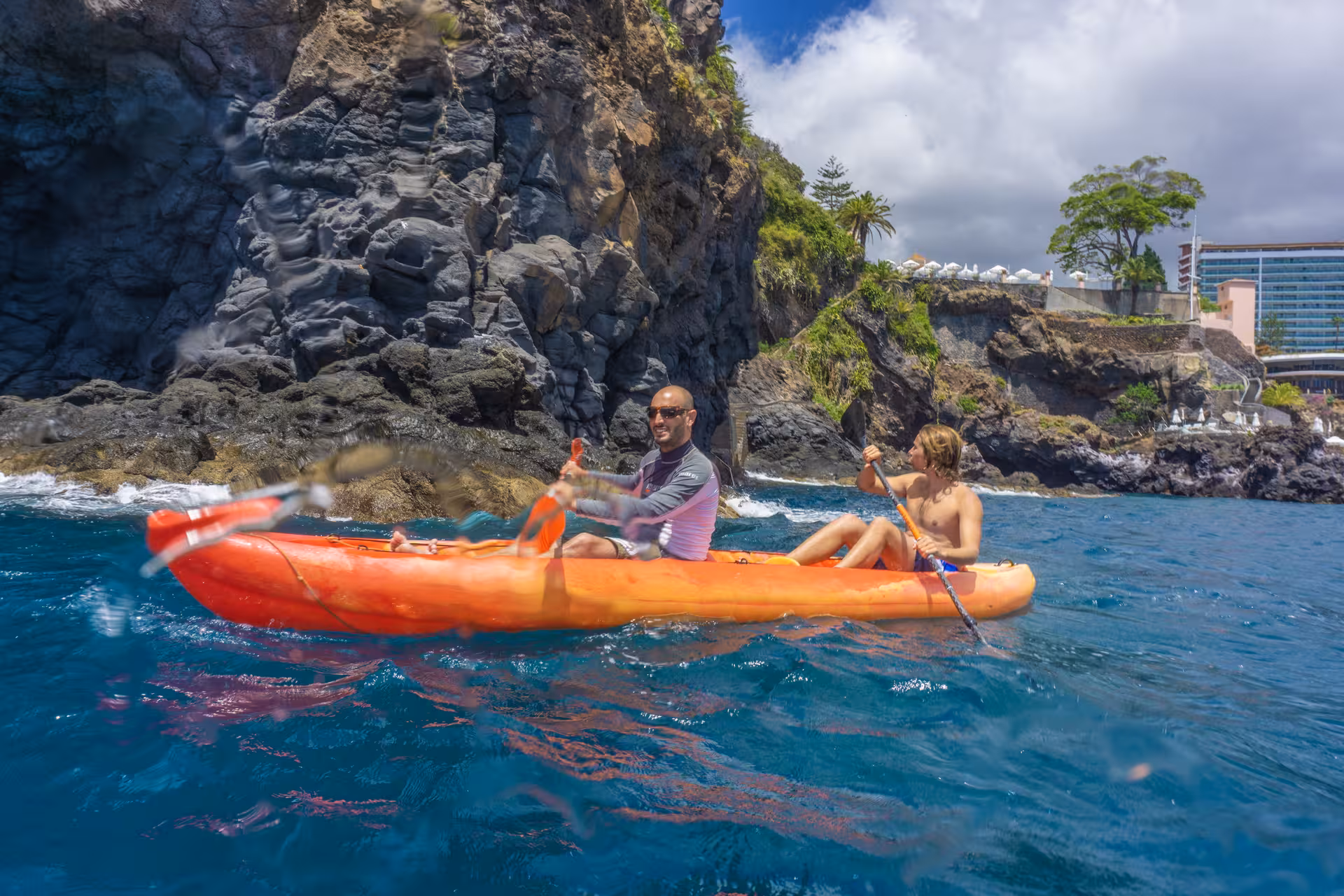 Scenic kayak tour along rugged cliffs with two paddlers enjoying a sunny day on the water.