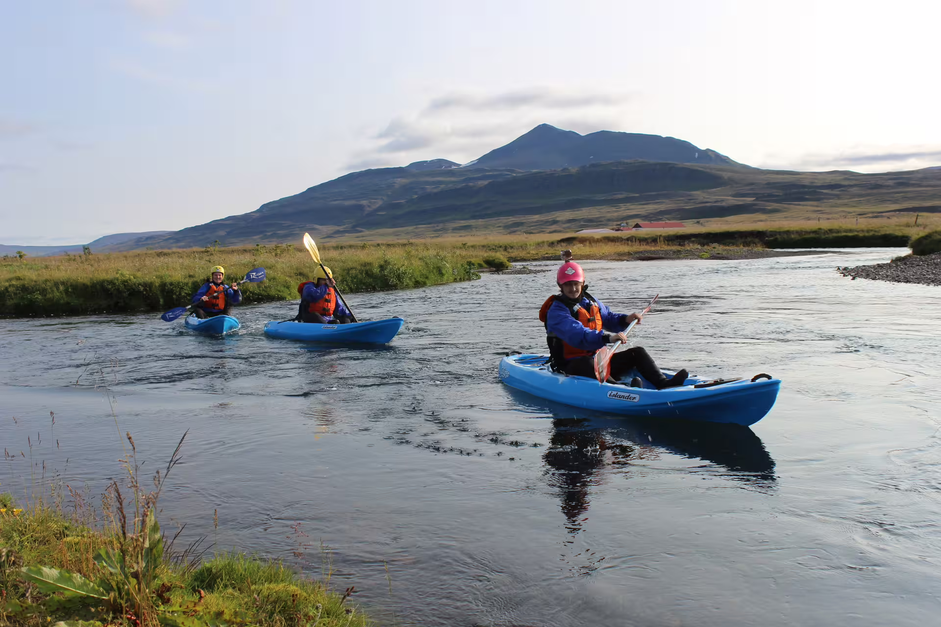 Kayakers enjoy a scenic adventure on Iceland's Svartá River, surrounded by picturesque landscapes and clear blue waters.