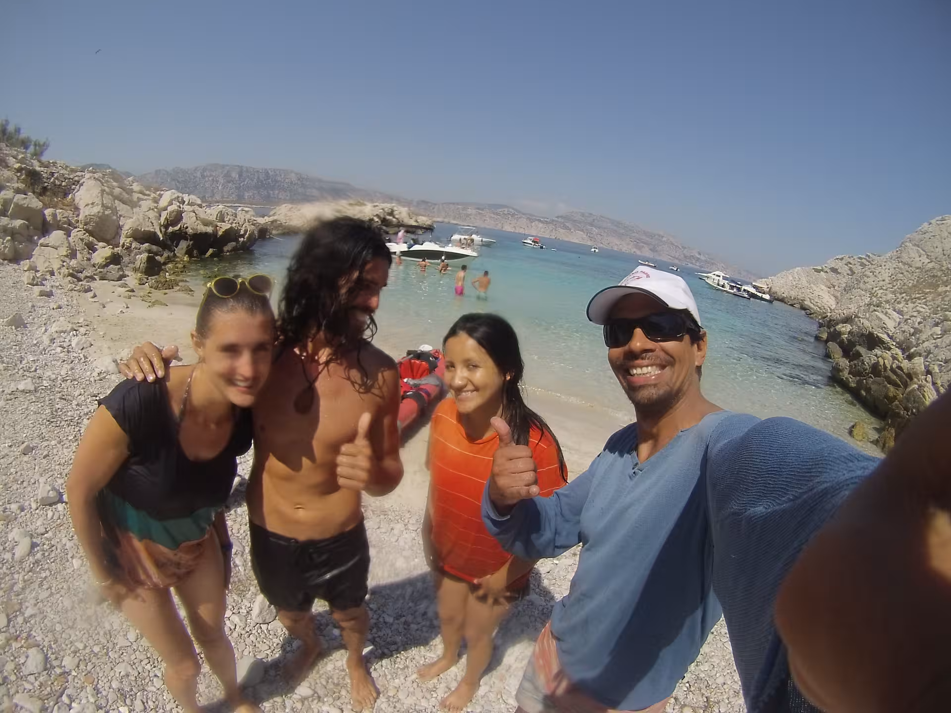 Happy group selfie on a Calanques beach after kayaking near Marseille islands, turquoise lagoon and boats in the bay