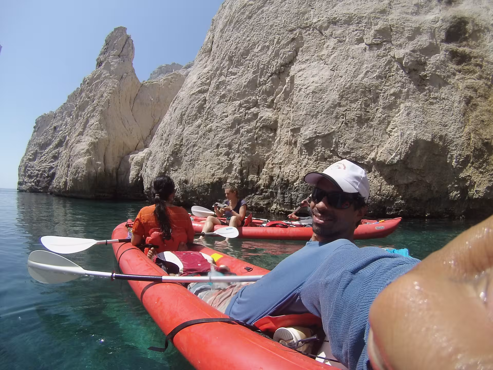 Groupe en kayaks rouges au pied des falaises, eau cristalline lors du tour kayak Presqu’île de Giens